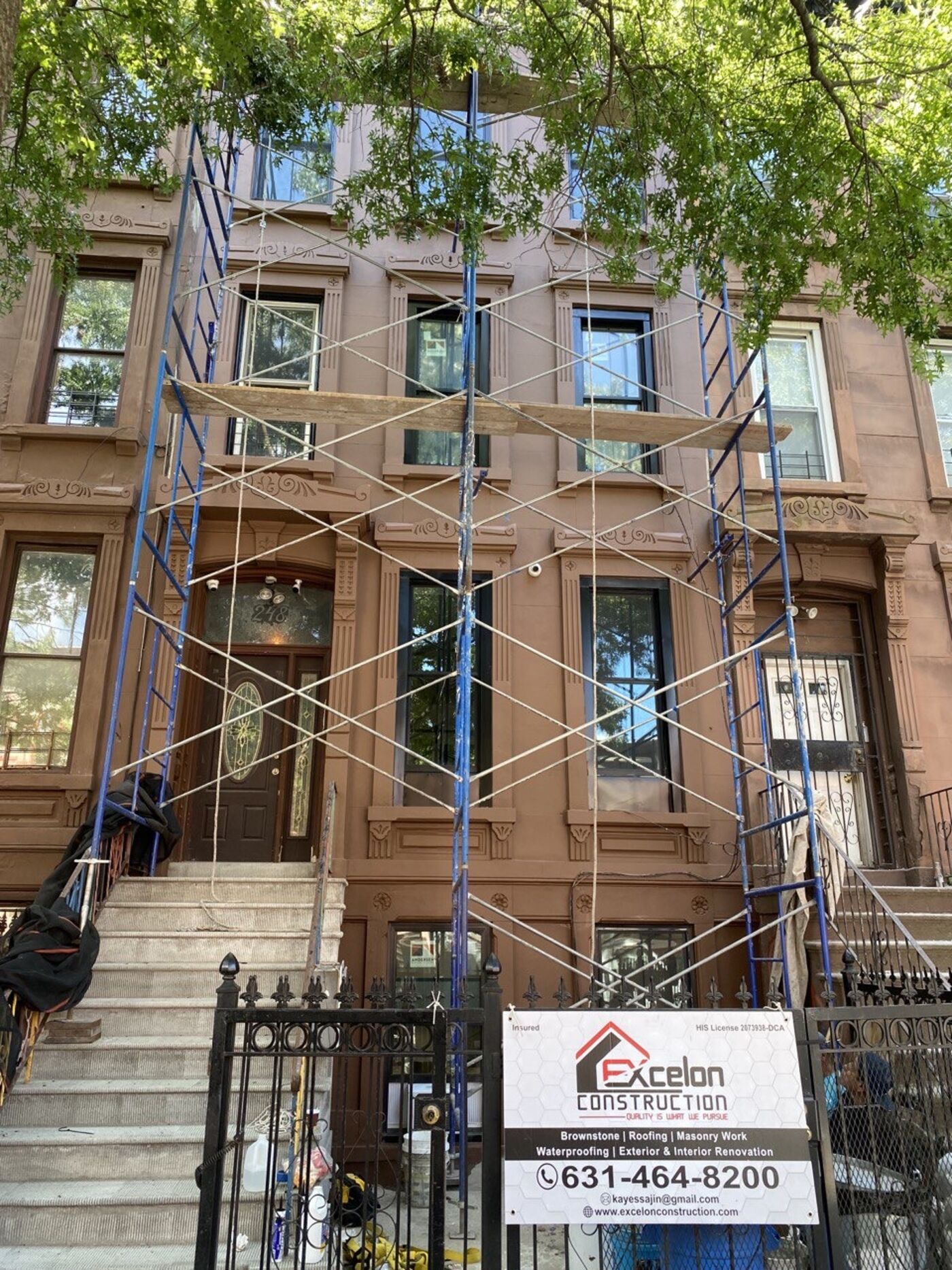 Full facade after restoration — stoop, brownstone, and cornice in unified finish.