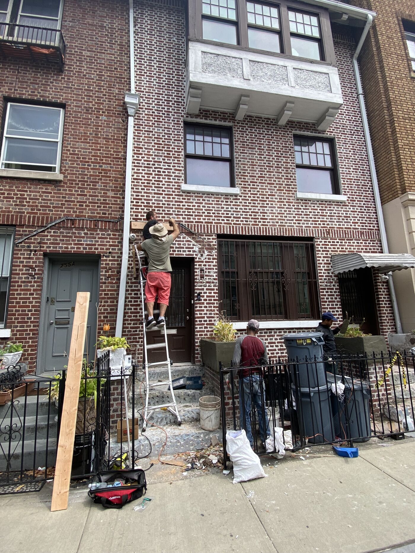 Restored stoop with cornice installation visible above.